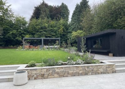 Elegant lines contrast with the natural sandstone cladding on the raised beds.